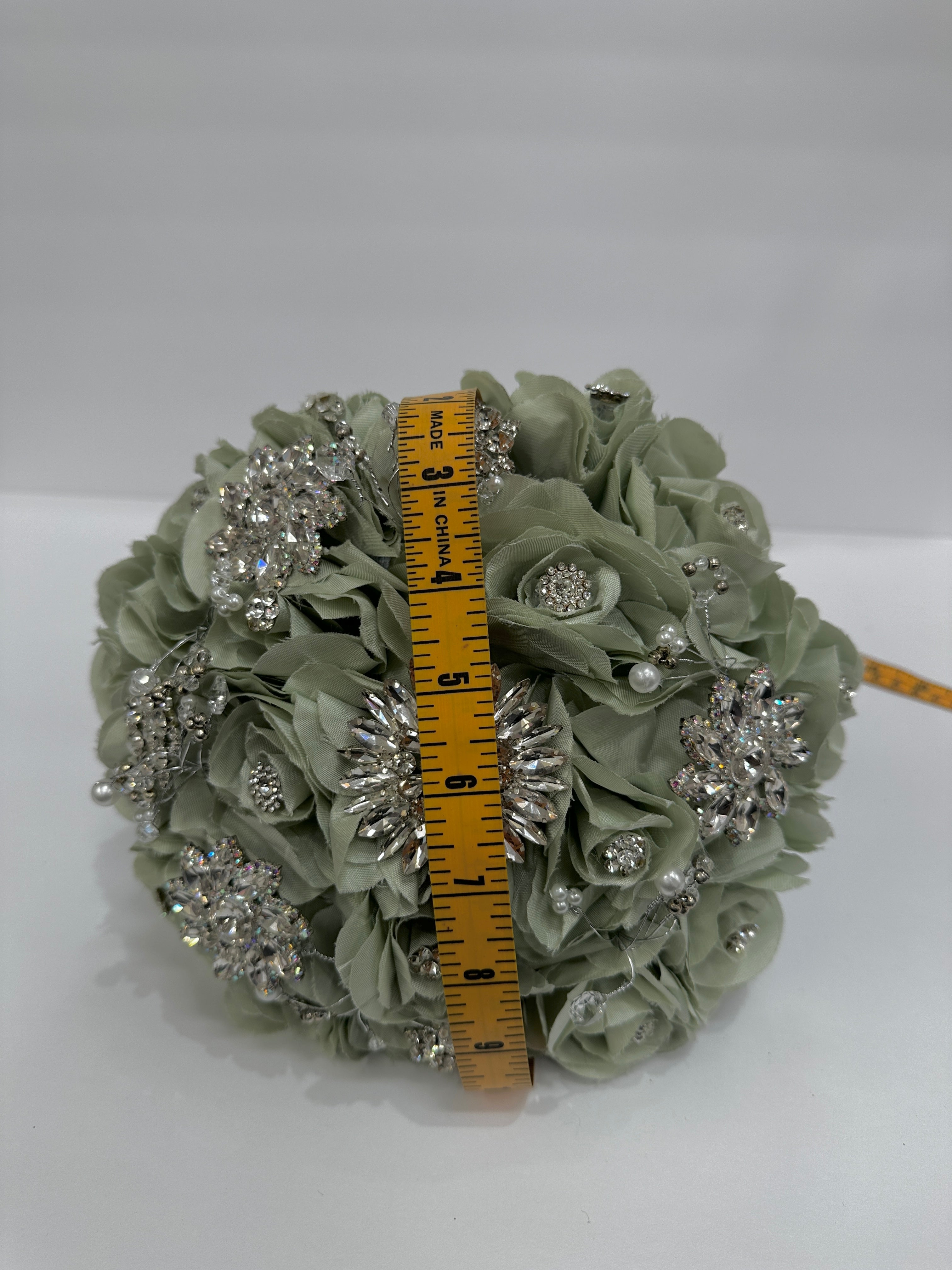 Decorative ball with rhinestones and a measuring tape for scale on a white background