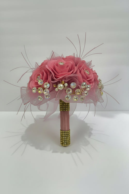 Pink floral bouquet with beads and ribbons on a white background