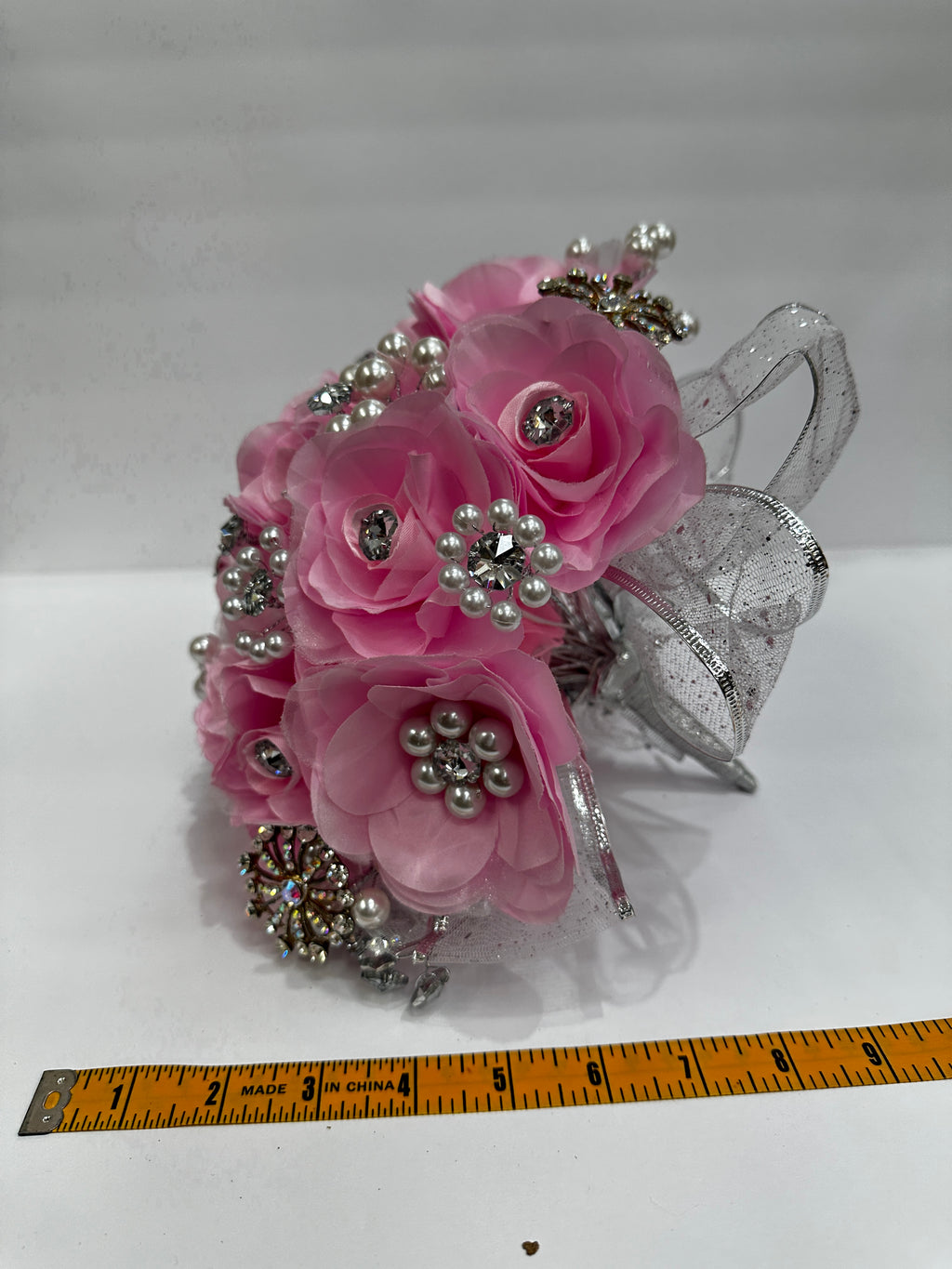 pink bouquet with silver application and pearl beadings. measuring tape measuring about 9 inches across