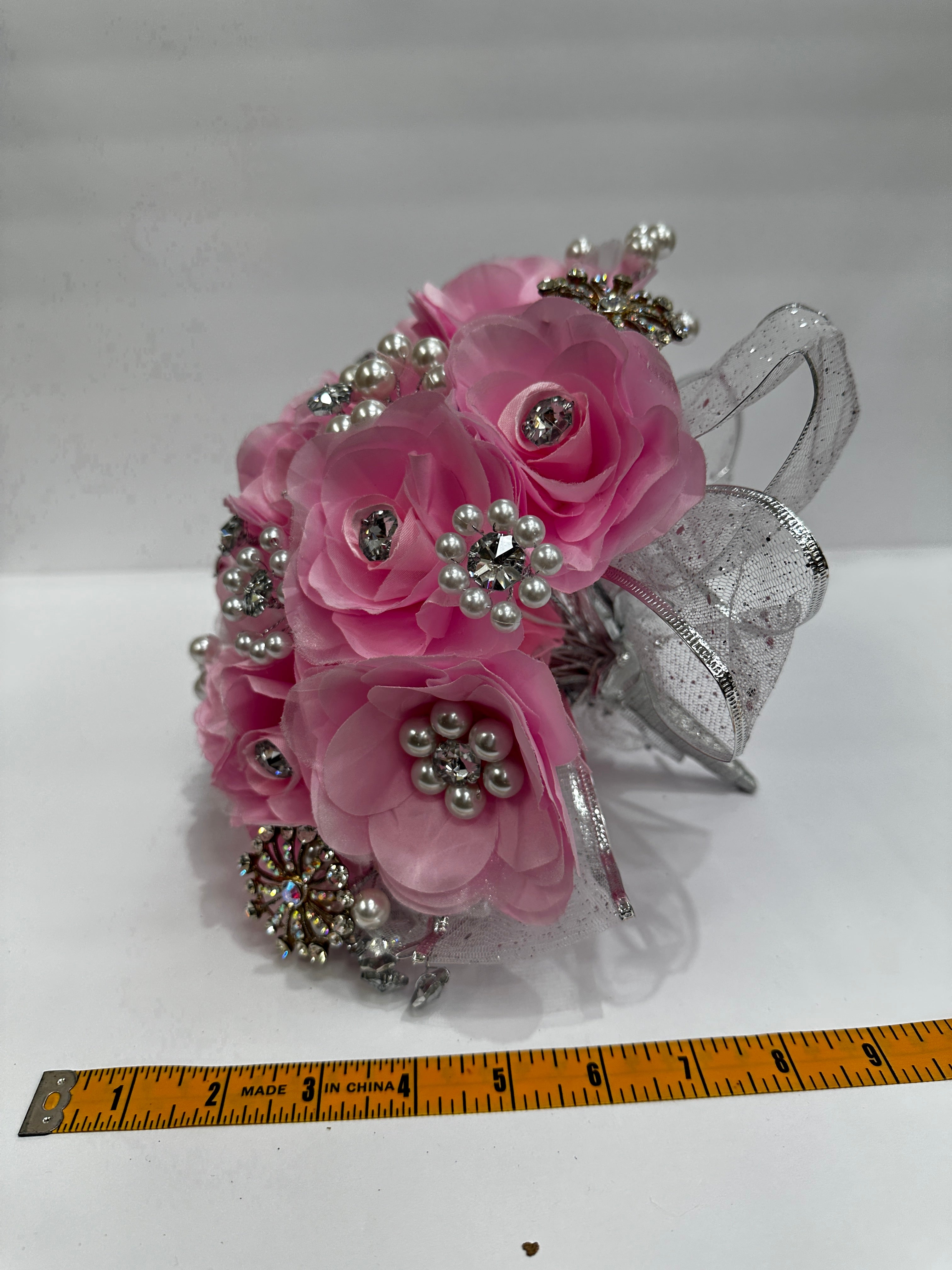 pink bouquet with silver application and pearl beadings. measuring tape measuring about 9 inches across